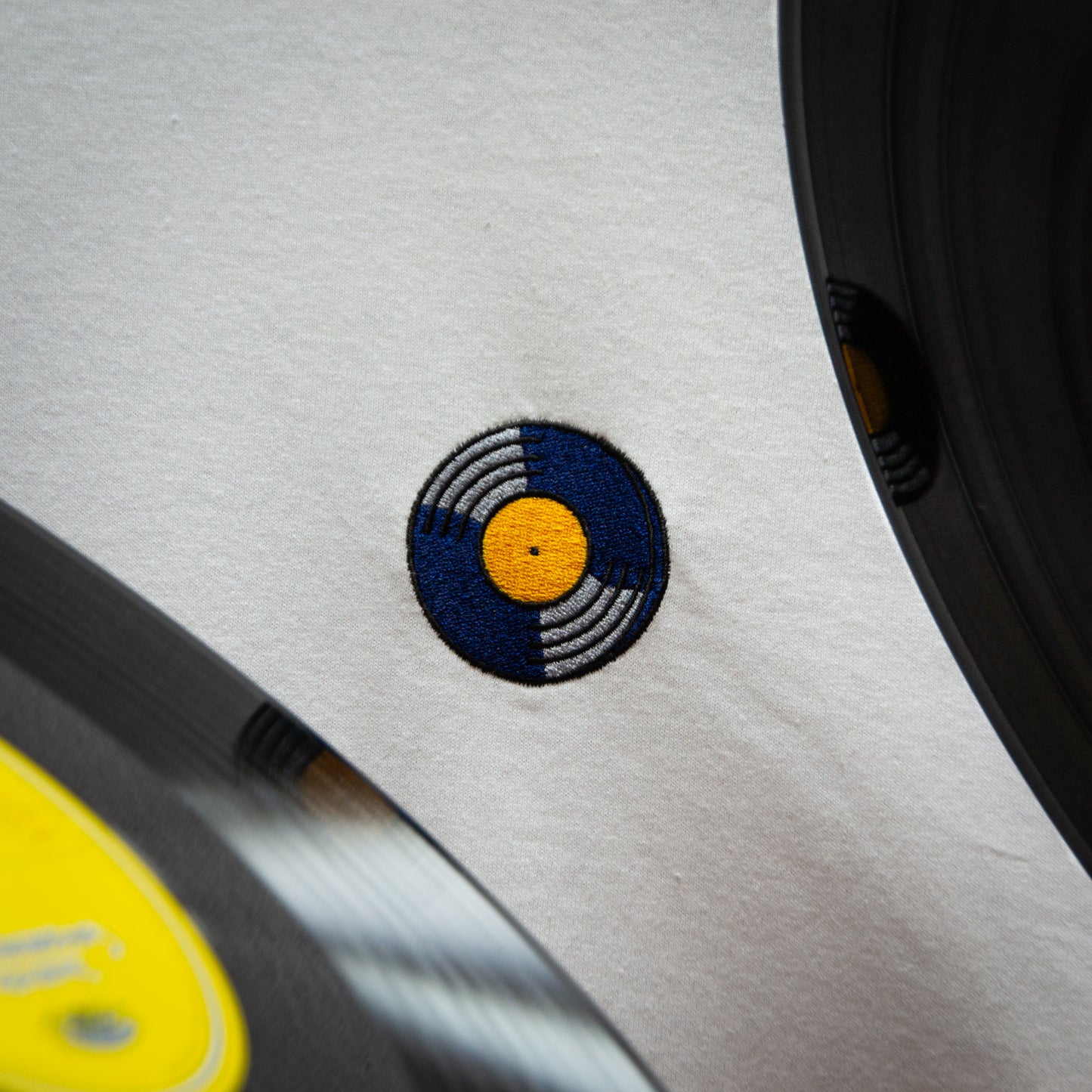 Close-up of STILL SPINNING design with a vinyl record embroidered logo