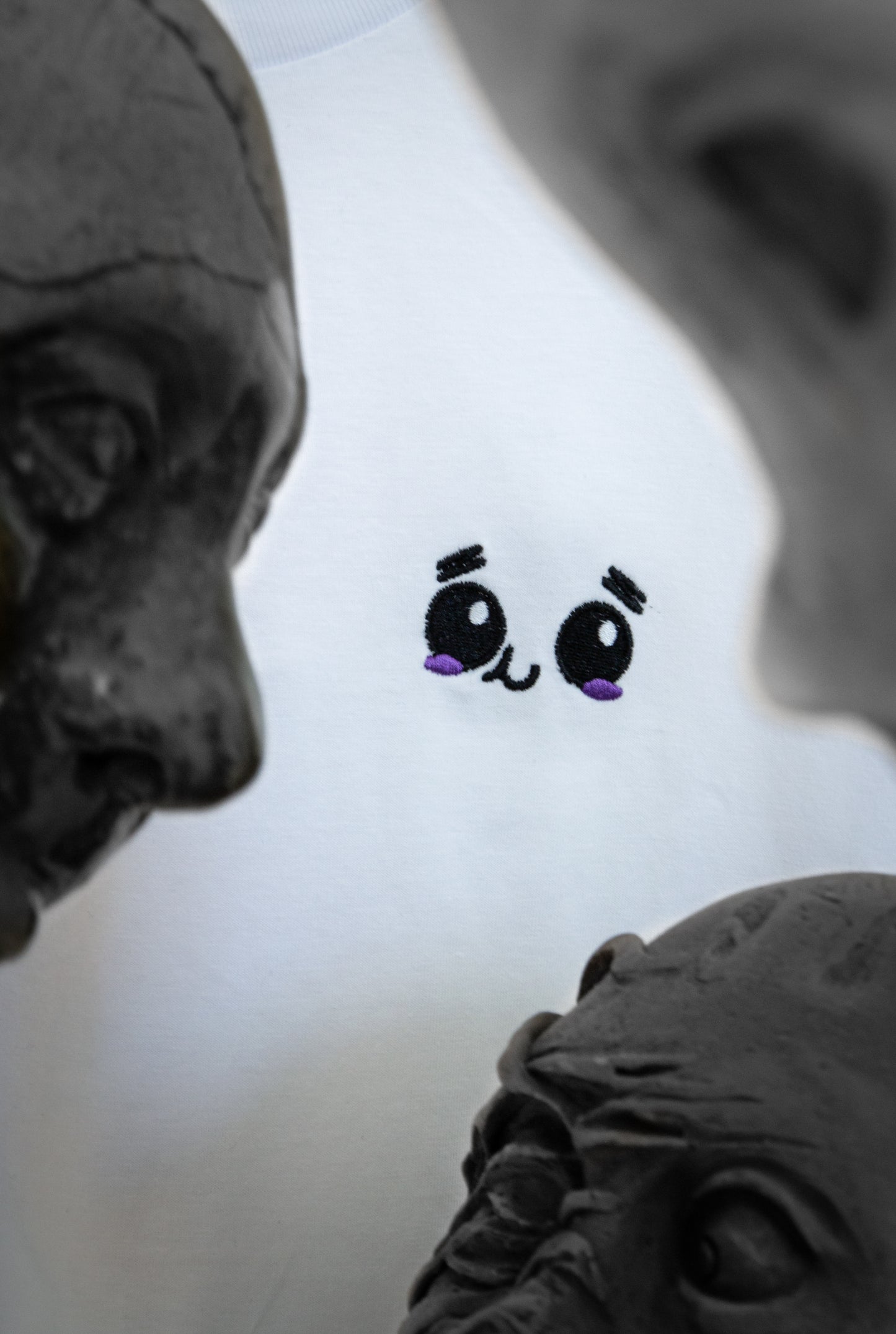 Close-up of the UNDERSTAND design with an embroidered face surrounded by different sculpted heads