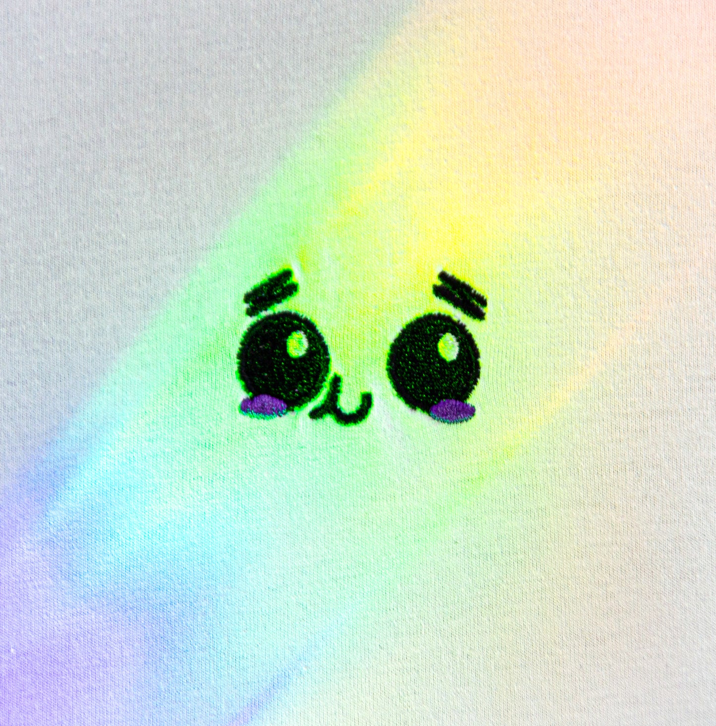 Close-up of the UNDERSTAND design with an embroidered face shined on by rainbows